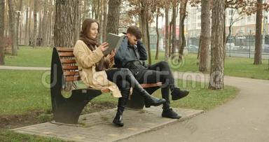 女人读一本书，而男人一<strong>起坐</strong>在冬天公园的长凳上听耳机里的音乐。